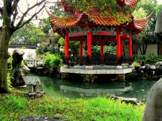 The pretty red pagoda rests on rocky pillars in the pond