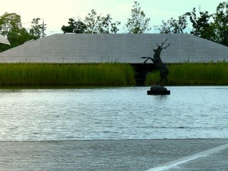 A prancing stag sculpture stands in the pond