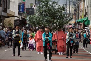 Men wearing festival coats walk ahead of the priests