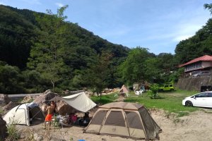 Camping on the riverside beach with the guesthouse in the background