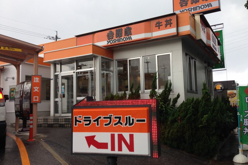 Yoshinoya's many restaurants are trimmed in orange and white with its name in kanji and English written in black
