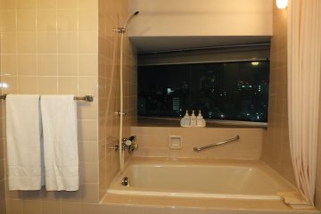 <p>อ่างอาบน้ำพร้อมและหน้าต่างสำหรับชมวิวของเมืองนาโกย่ายามค่ำคืน</p>