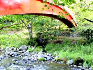 The red bridge over the shallow rushing waters gives a perfect contrast to the green surroundings