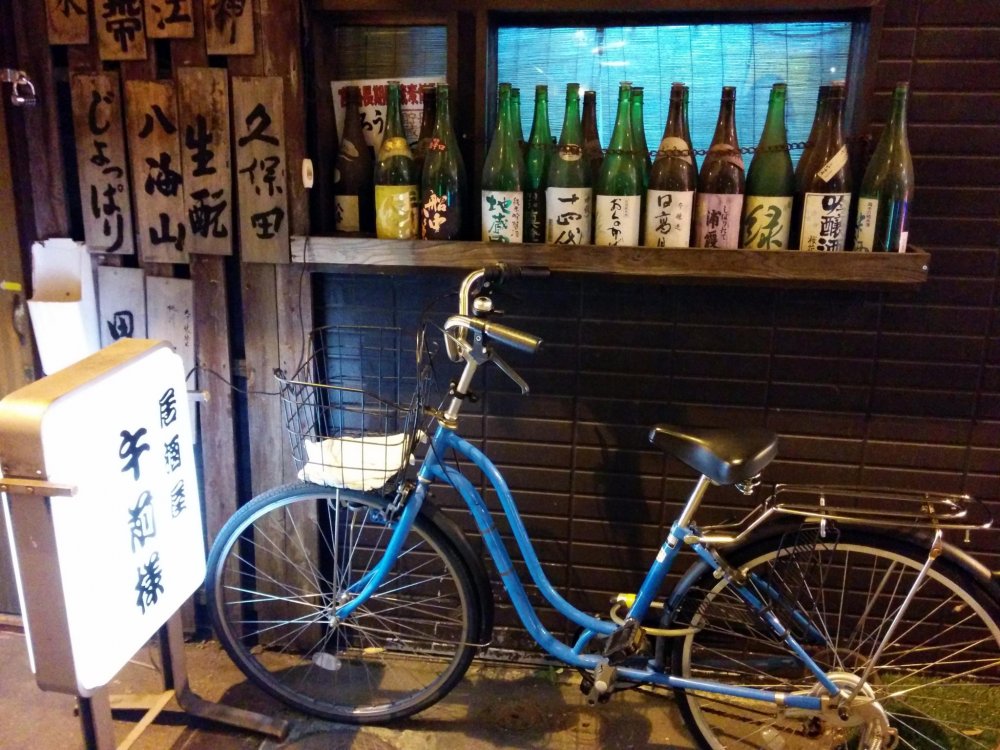 A local parks his bike in front of his favorite bar. The ride here was easy, but he will be walking his bike home because of the zero tolerance on alcohol law when operating a vehicle in Japan.&nbsp;