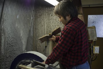 <p>Hideo Takamura&nbsp;hitting the carving whetstone to ensure more friction during the buffering process.</p>