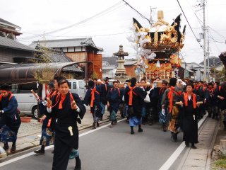 A group of Japanese men carrying the portable shrine down the street.