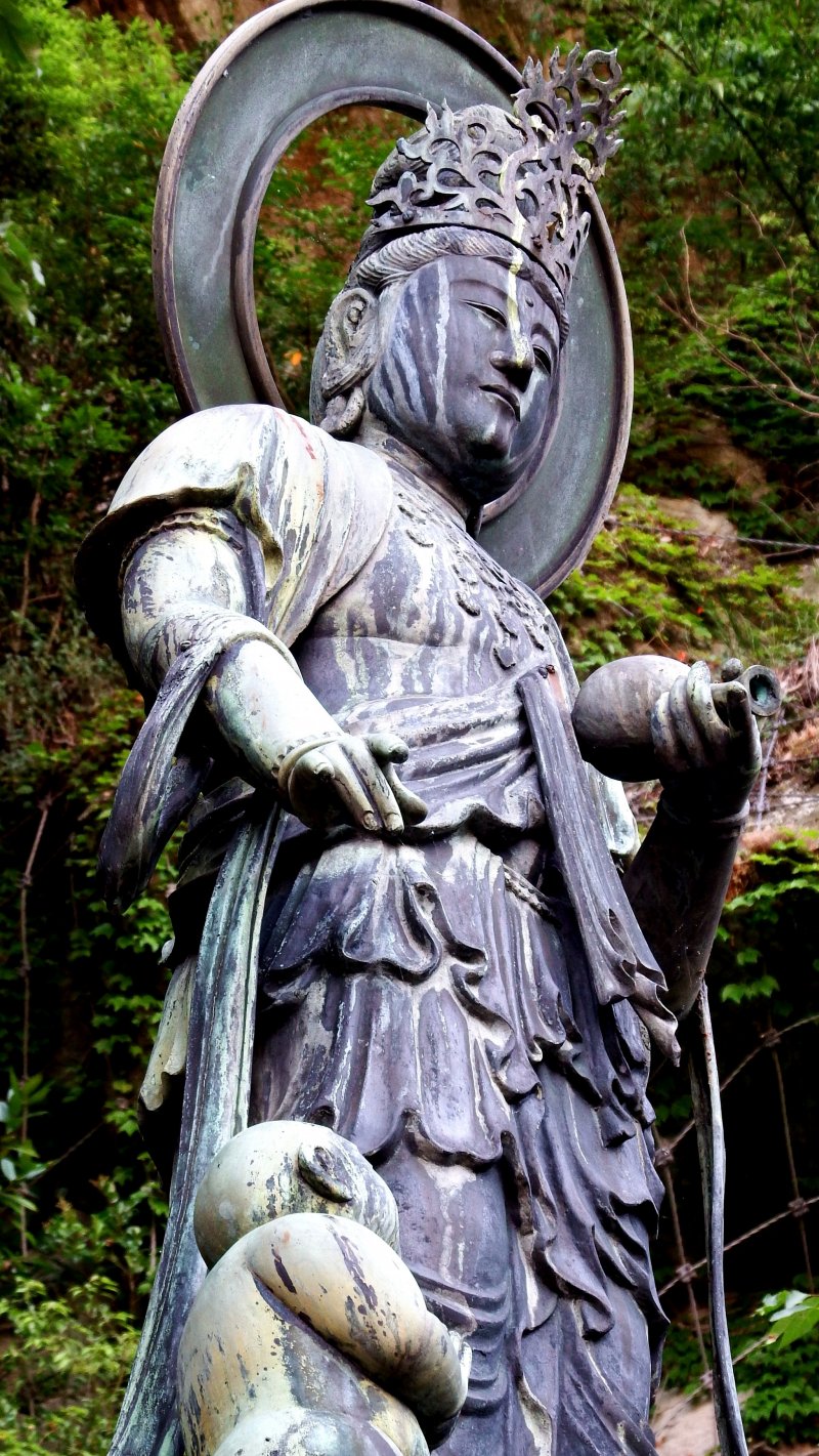 <p>Close up of the statue of the Goddes of Mercy for children, with a child clinging to her leg</p>