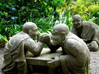 Statues of monks holding an arm wrestling match