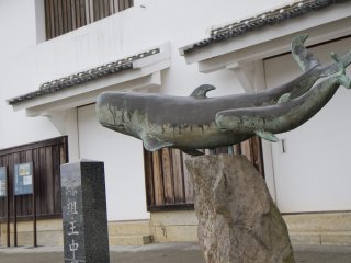 Một bức tượng kỷ niệm lịch sử quá khứ của thị trấn về săn bắt cá voi trước tòa nhà Nakao 250 năm tuổi