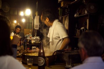 <p>A chef talks with guests at a yakitori shop</p>