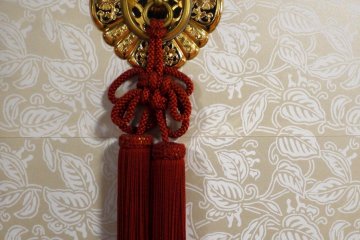 <p>Red tassels decorate an ornate finger plate on a sliding door</p>