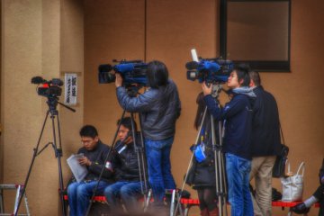 บรรดานักข่าวทีวีมาถึงและตระเตรียมเครื่องไม้เครื่องมือเพื่อรอเวลาพิธีเริ่มขึ้น