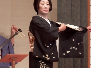 Cánh hoa anh đào màu trắng và cây liễu được vẽ trên màu đen của bộ kimono của cô ấy