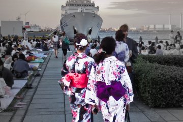 <p>A couple of young women wait patiently for the display to begin near the &#39;Aka-Renga&#39; area. Note the large ship in the background that belongs to the Japanese Coast Guard, which maintains a small patrol base here</p>