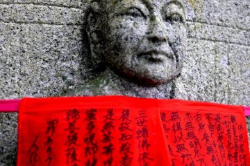 <p>Sutras written on a statue&#39;s red apron</p>