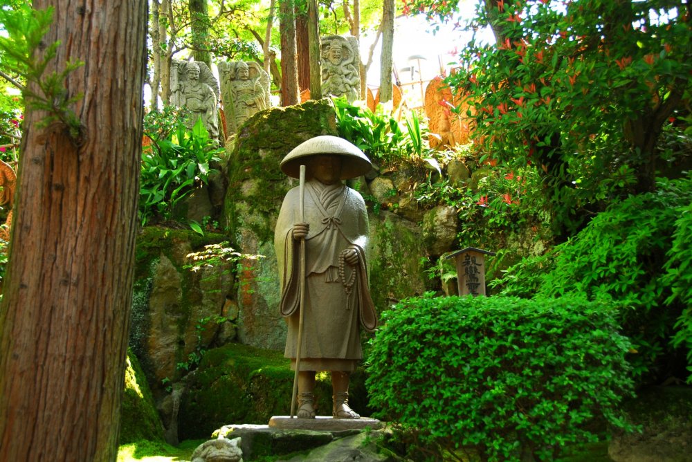 Statue of Monk Shinran standing silently in the woods at the back of the Main Hall