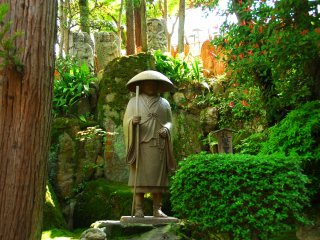 Statue of Monk Shinran standing silently in the woods at the back of the Main Hall