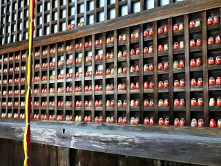 The deity is enshrined&nbsp;in framework filled with Daruma dolls. What could the meaning of the Daruma dolls being places in pairs mean?