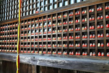 <p>The deity is enshrined&nbsp;in framework filled with Daruma dolls. What could the meaning of the Daruma dolls being places in pairs mean?</p>