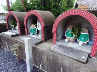 Three pairs of jizo statues stand in a corner of the temple grounds