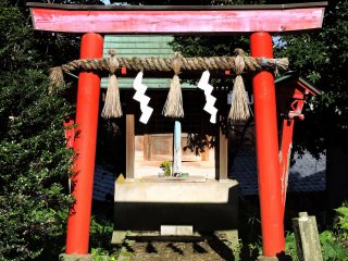 Brilliant red torii gate stands out in the otherwise plain temple grounds