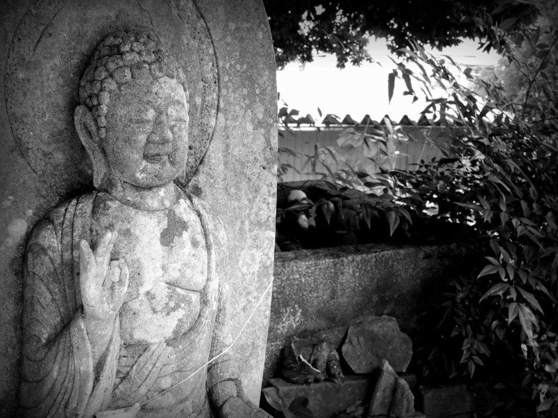 <p>Stone Buddha Statue watching over the cemetery of broken jizo statues in the old well (in the back)</p>