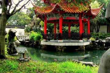 <p>The pretty red pagoda rests on rocky pillars in the pond</p>