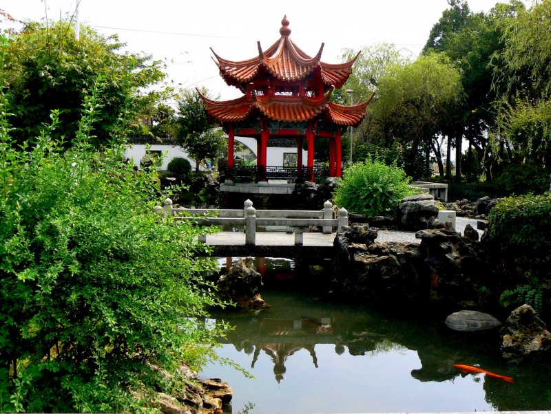 <p>A bridge spans the pond near the pagoda</p>
