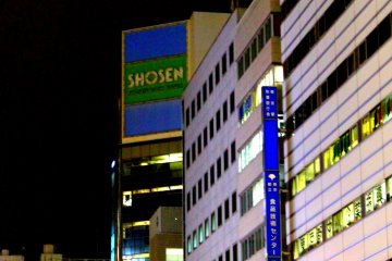 <p>Shosen Book Tower is not easy to miss, as it stands towering at a street corner with windows reflecting against the lights, shining in blue</p>