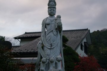 <p>A tall statue of Kannon, with children</p>