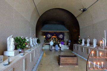<p>Visitors praying in front of the main altar at the end of the tunnel</p>