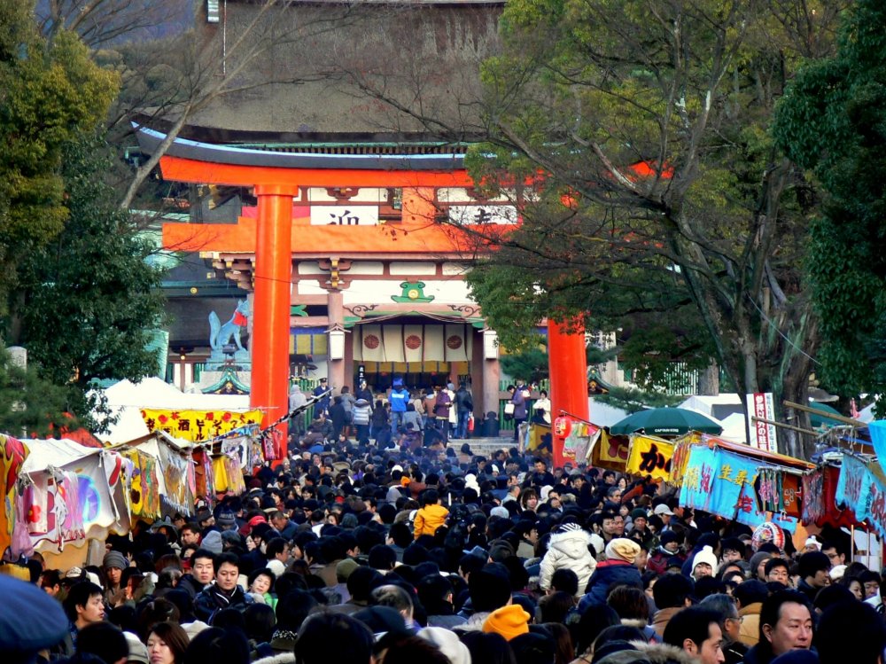 Mọi người chen chúc dưới cổng torii đỏ
