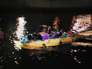 Illuminated boat floating on Dojima River going under Yodoyabashi and Ooebashi Bridges
