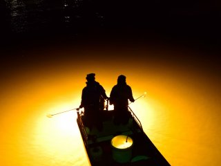 川面に広がった光芒が、漁師のシルエットを浮かび上がらせる（新町川）
