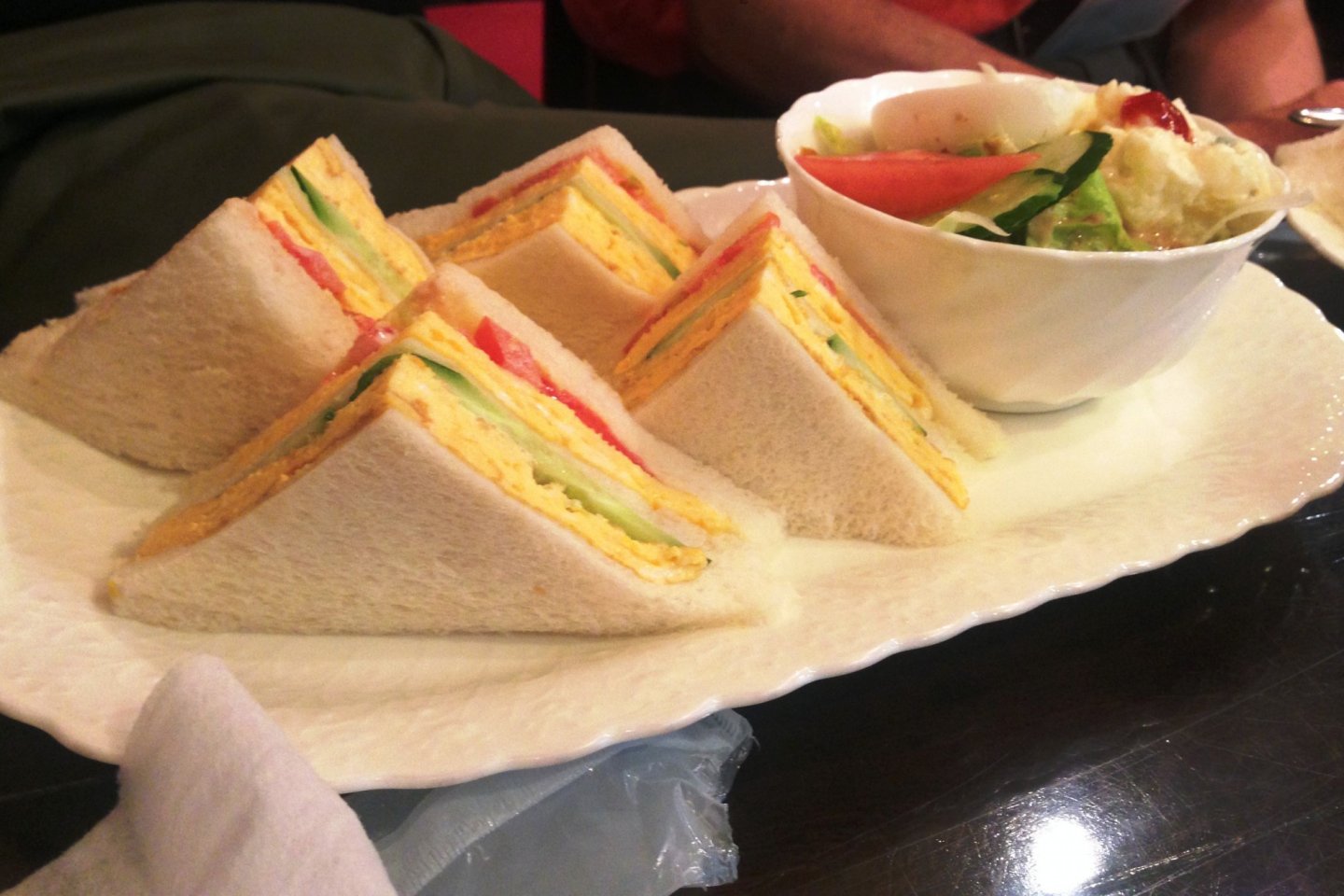 Sandwich gaya klub klasik dengan salad hijau. Perhatikan gaya presentasi tempo dulunya dengan roti putih dan tanpa kulit.