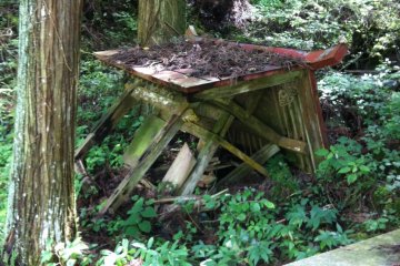 An unkept shrine covered in vegetation, possibly destroyed by recent heavy rain