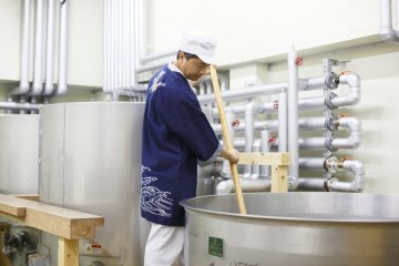 A workers stirs a vat of sake mash in a Chiba brewery