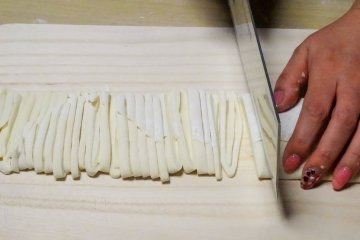 Slicing the dough for udon into noodles