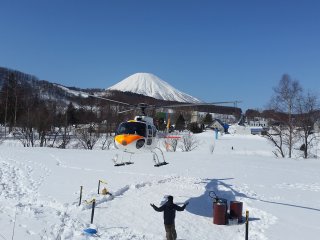 Helikopter mendarat dengan Gunung Yotei di latar belakang