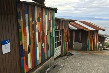 Look for these colourful walls by Rikuji Makabe. They are made of various scrap materials found around the island and brighten up the walls in different spots around the town.