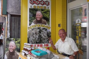 The &#39;Bee-beard oyaji&#39; outside his shop: note the small plastic box of bees on the table