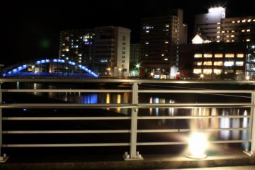 Overlooking the blue-lighted arched bridge and the buildings behind