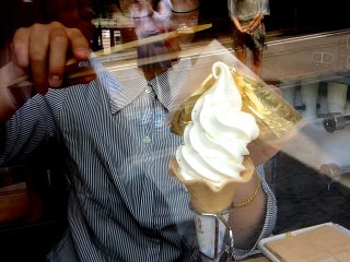 A careful pair of bamboo tongs helps the thin sheet of gold leaf hug onto the ice-cream
