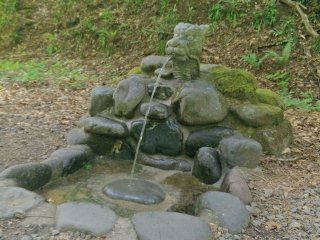A dragon's head fountain on the path to the pond