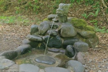 A dragon's head fountain on the path to the pond