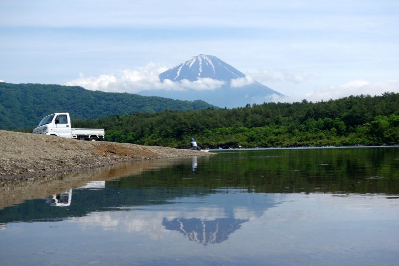 A man throws his fishing rod into Lake Saiko on a calm sunny day