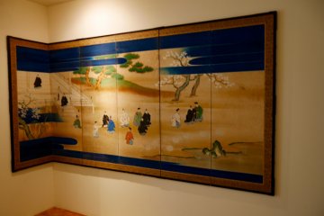 Traditional Japanese panel art, byobu, lines the walls of this side room