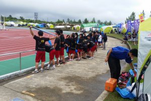 Young athletes watch runners amid a busy group of school tents