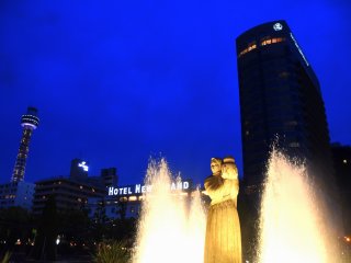 Dewi Air berdiri dengan Hotel New Grand di bagian belakangnya
