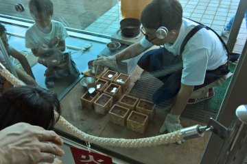 Children watching their design being filled with tin